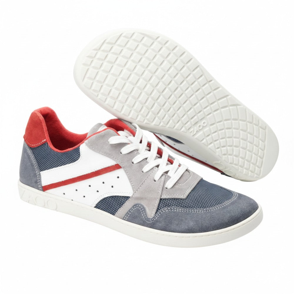 Ein Paar stylische BREAQ Darkblue-Sneaker von ZAQQ, die eine auffällige Kombination aus grauen, weißen, roten und blauen Einsätzen aufweisen. Diese Schuhe haben weiße Schnürsenkel und eine markante strukturierte Sohle. Ein Schuh steht aufrecht, während der andere auf der Seite liegt, wodurch das Profilmuster betont wird.