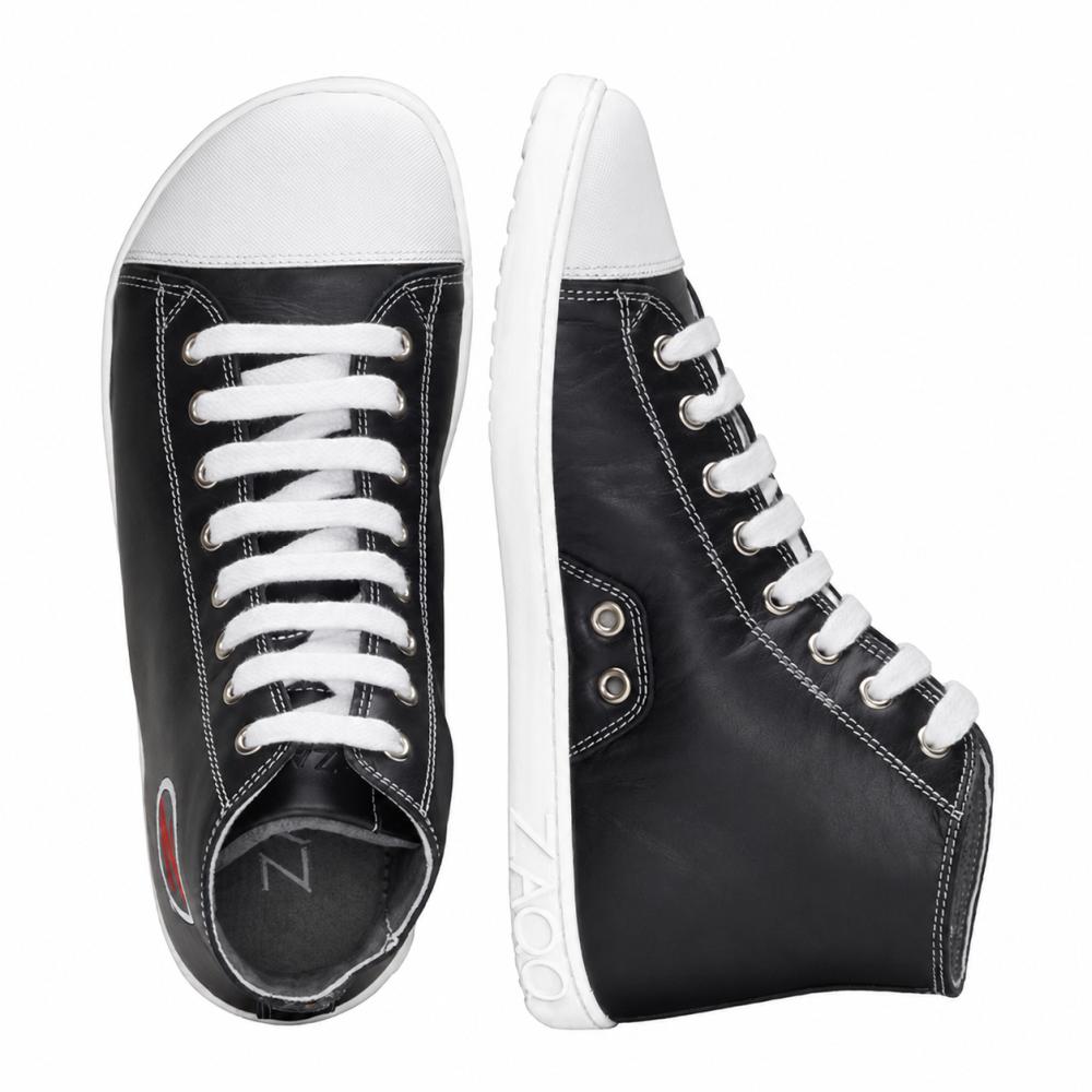 Para stylowych czarnych wysokich sneakersów od ZAQQ CHUQQS z białą kauczukową podeszwą i sznurówkami. Lewy but stoi pionowo, podczas gdy prawy leży na boku, pokazując eleganckie logo w pobliżu pięty.