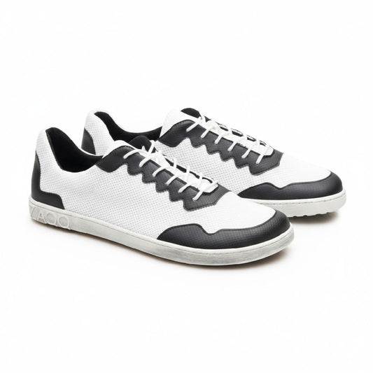 Wir präsentieren die DUPLEQ Black White Vegan Sneaker von ZAQQ: Diese stylischen schwarz-weißen Schuhe haben weiße Schnürsenkel und Sohlen und sind mit einem strukturierten Muster aus atmungsaktivem Meshgewebe gestaltet. Ein Logo ziert die Ferse und verleiht diesen veganen Barfußschuhen ein schlichtes Aussehen, da sie nebeneinander auf einem schlichten weißen Hintergrund stehen.