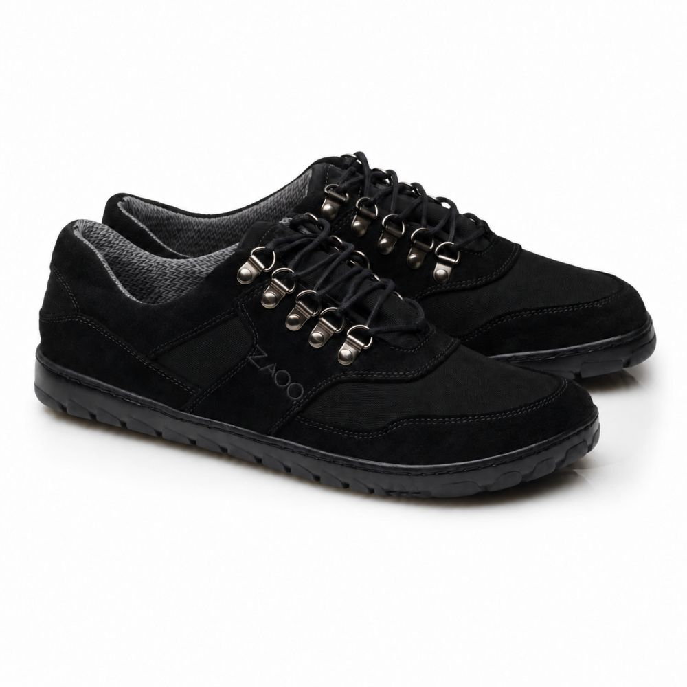 Die HIQE Low Black Waterproof-Schuhe von ZAQQ haben schwarze Schnürsenkel, silberne Ösen und eine Outdoor-Sohle. Ihre strukturierte Sohle passt perfekt zu einer Mischung aus glatten und wildlederähnlichen Materialien im oberen Teil. Der Markenname ZAQQ ist an der Seite deutlich sichtbar.