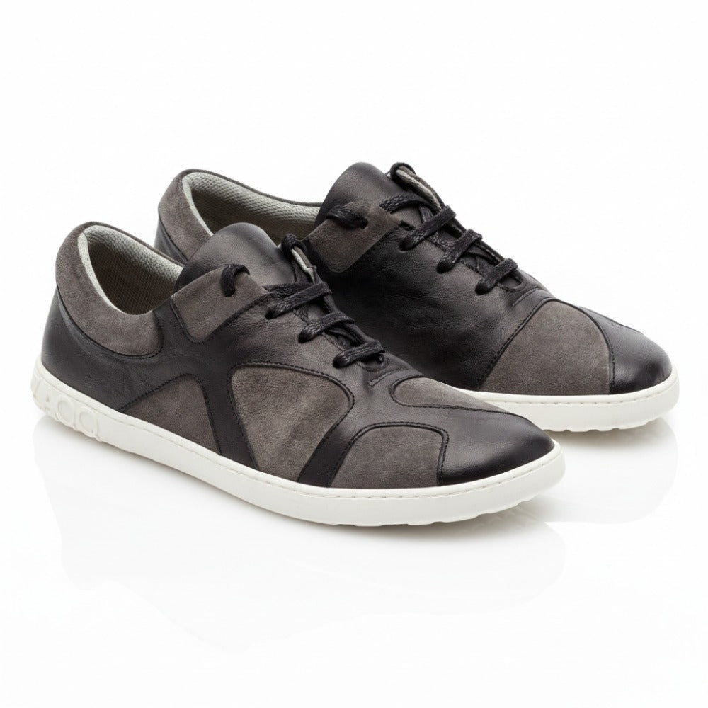 Wir präsentieren den QAANAAQ Black von ZAQQ: ein stilvolles Paar lässiger Sneaker in Schwarz und Grau mit weißer Sohle, gefertigt aus leichtem Veloursleder für mehr Komfort. Diese Schuhe verfügen über schwarze Schnürsenkel und eine luxuriöse Mischung aus Leder- und Wildledertexturen, die sich kunstvoll vor einem makellosen weißen Hintergrund abheben.