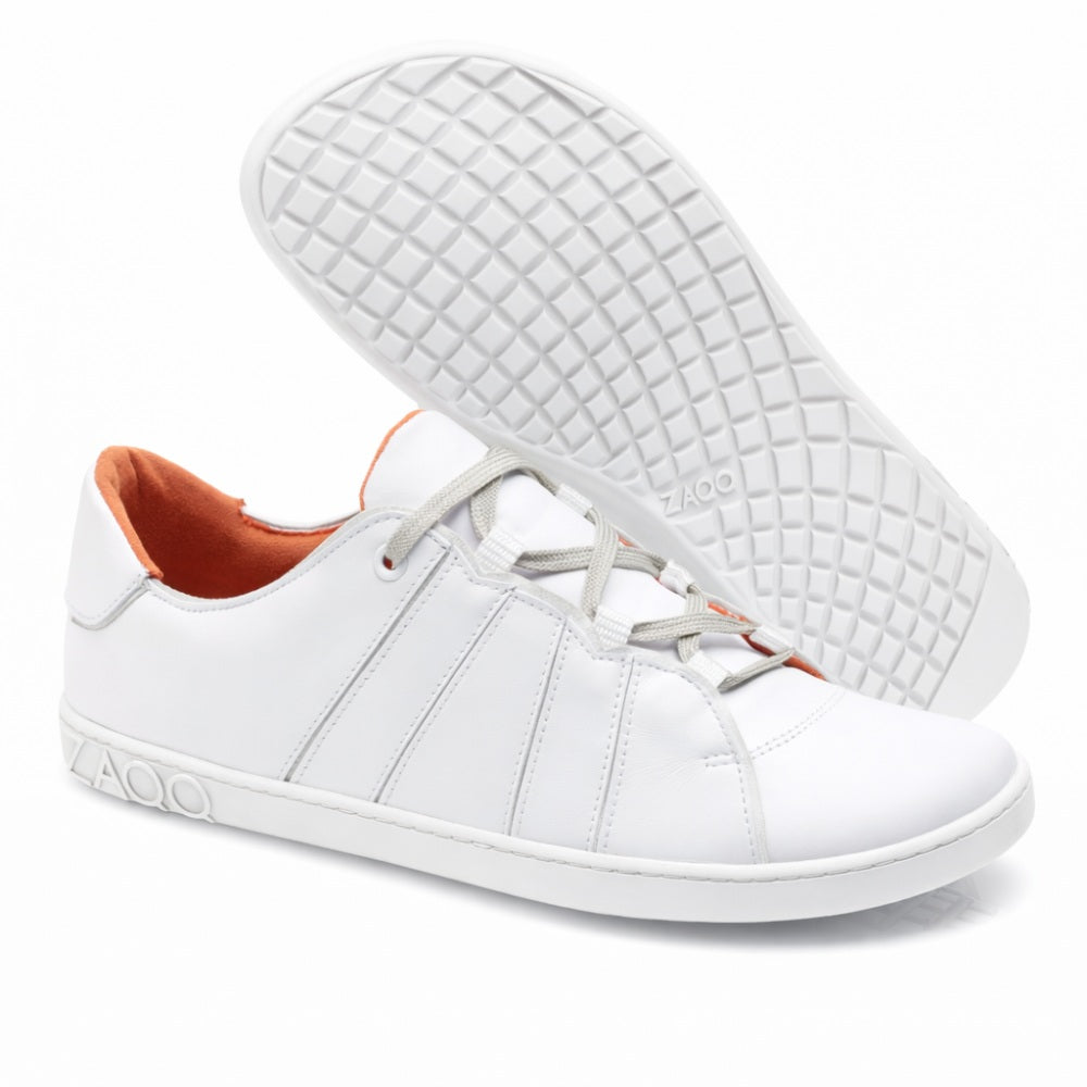 Wir präsentieren die QQQ Low White Sneakers von ZAQQ, ein elegantes Paar aus hochwertigem Nappaleder. Diese Freizeitschuhe haben graue Schnürsenkel und ein leuchtend orangefarbenes Innenleben. Das Design umfasst aufwendige Seitennähte, wobei ein Schuh aufrecht steht und der andere geneigt ist, um die Sohle mit Waffelmuster zu zeigen. Der Markenname ZAQQ ist sowohl an der Seite als auch an der Sohle deutlich zu sehen und unterstreicht das charakteristische Barfußschuh-Design.