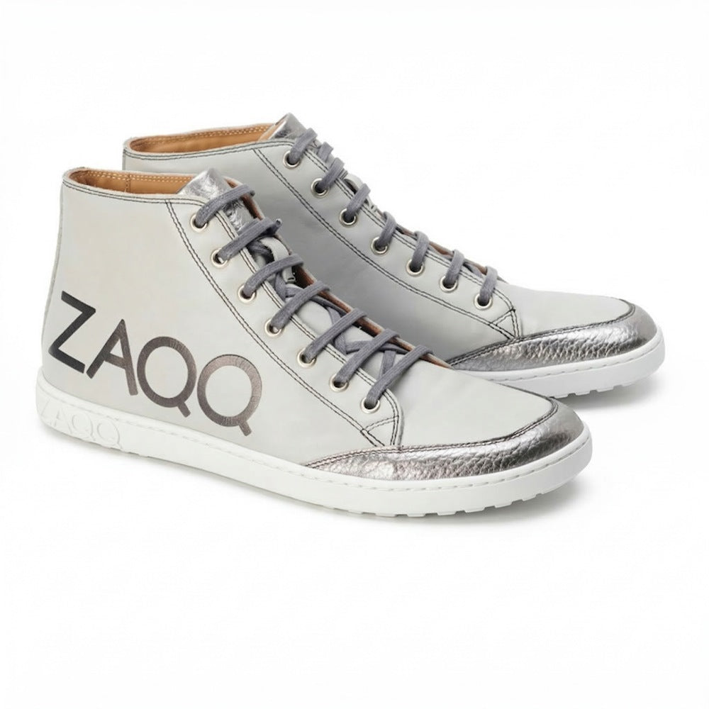 Entdecken Sie die ideale Kombination aus Stil und Komfort mit den SQYLA Grey High-Top-Sneakern von ZAQQ. Diese Sneaker sind mit silbernen Metallic-Akzenten und Markendetails verziert und aus hochwertigem Nappaleder gefertigt. Sie verfügen über ein klassisches Schnürdesign gepaart mit einer weißen Kautschuksohle, die für einen dezenten Used-Look sorgt.