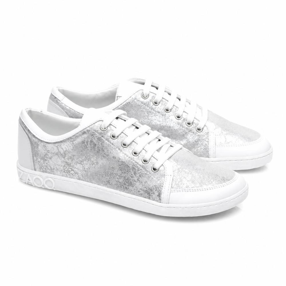 Przedstawiamy TIQQ Silver White od ZAQQ: Para stylowych sneakersów z wysokiej jakości skóry nappa z wyrazistą metaliczno-srebrną teksturą i białymi podeszwami. Te sneakersy wyposażone są w olśniewająco białe sznurówki, ozdobne szwy i charakterystyczny detal 4000 na boku podeszwy.